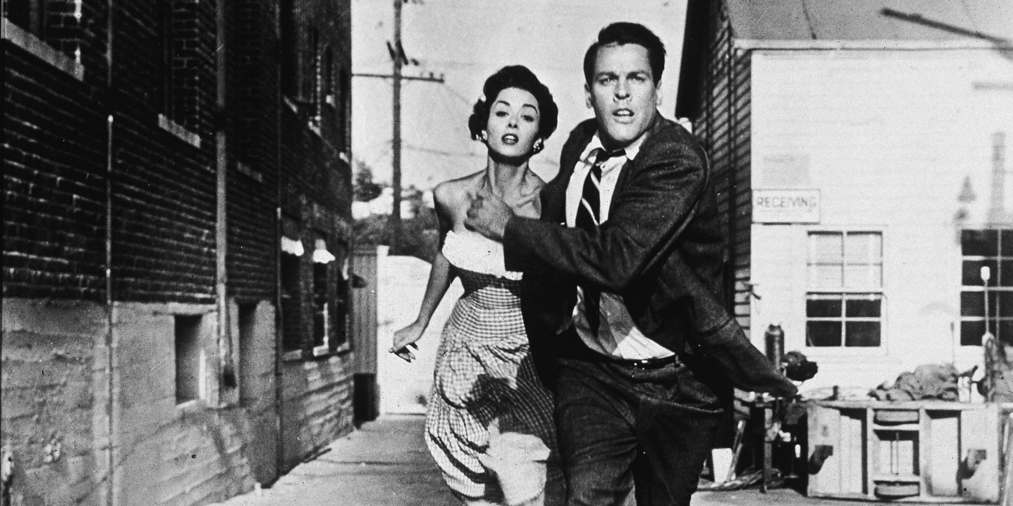 Dana Wynter and Kevin McCarthy in Invasion of the Body Snatchers running away and looking scared.