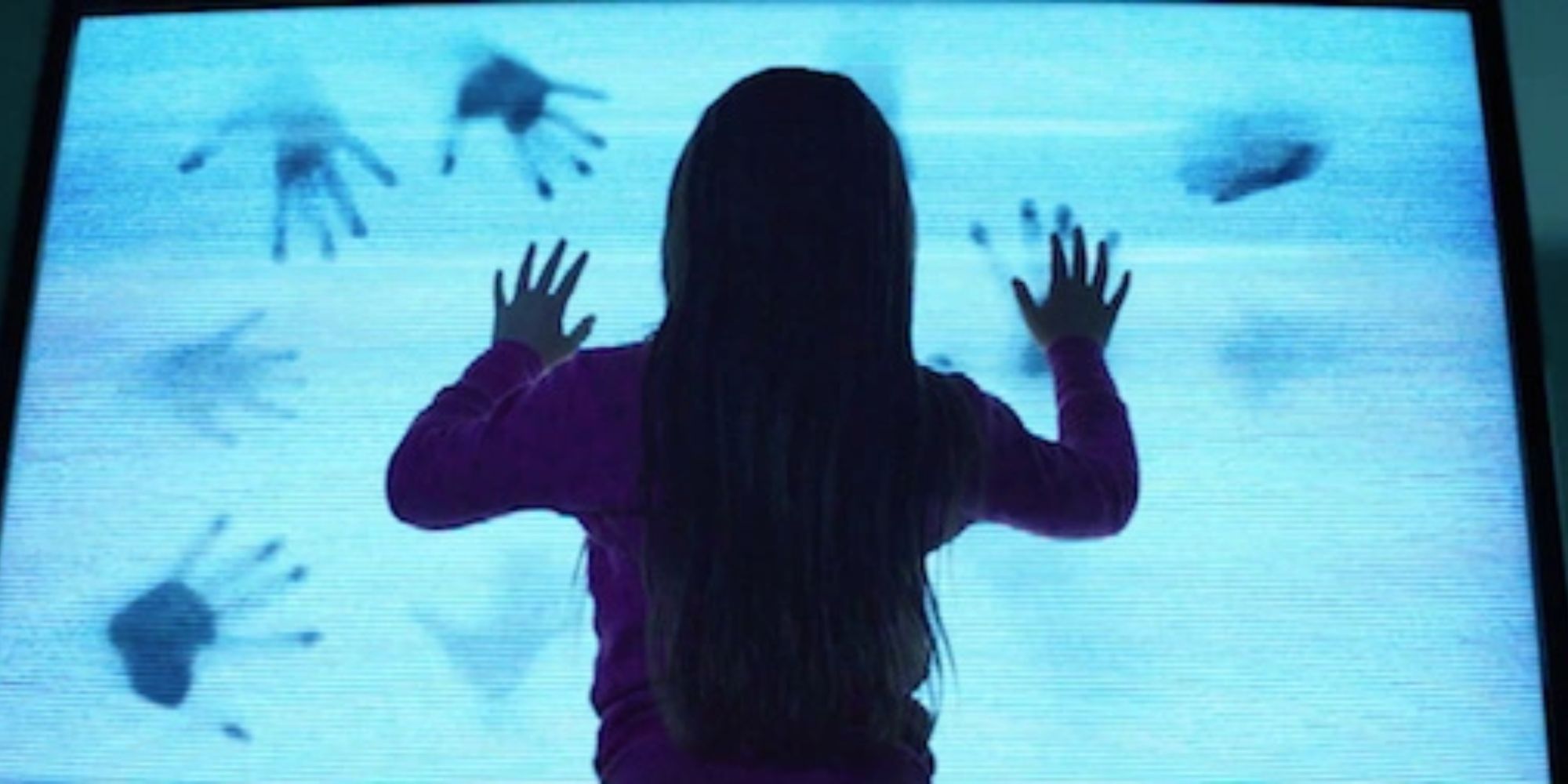 Uma cena do filme 'Poltergeist' de 2015.  Uma jovem pressiona o rosto contra uma TV estática enquanto marcas de mãos começam a aparecer na tela.