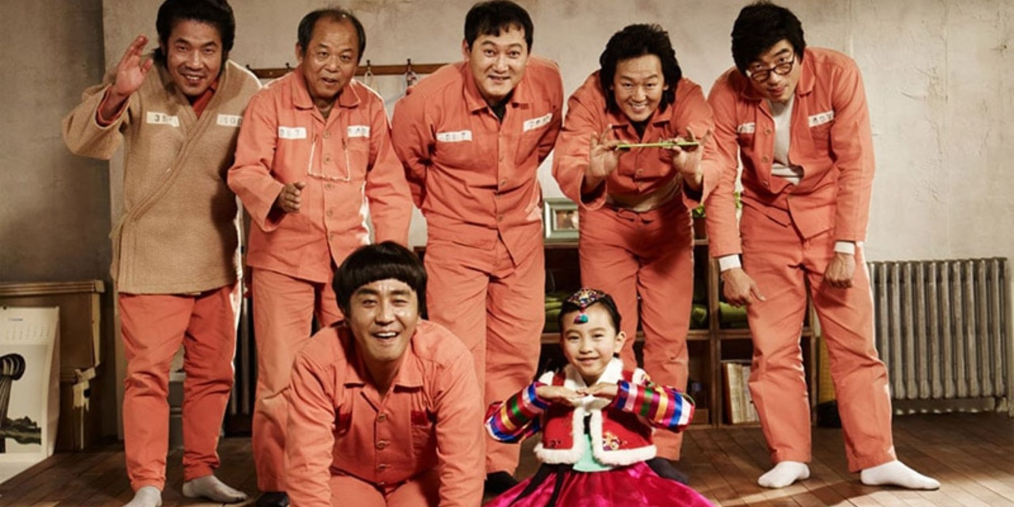 The cast (a young girl and six men in prison uniforms) smile and pose for Miracle in Cell No. 7.