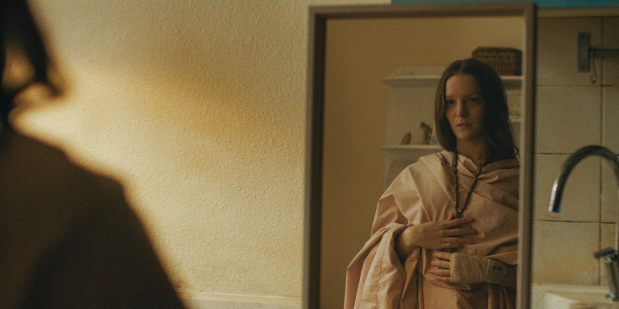 Une femme s'habille d'une robe de chambre et se tient devant un miroir.