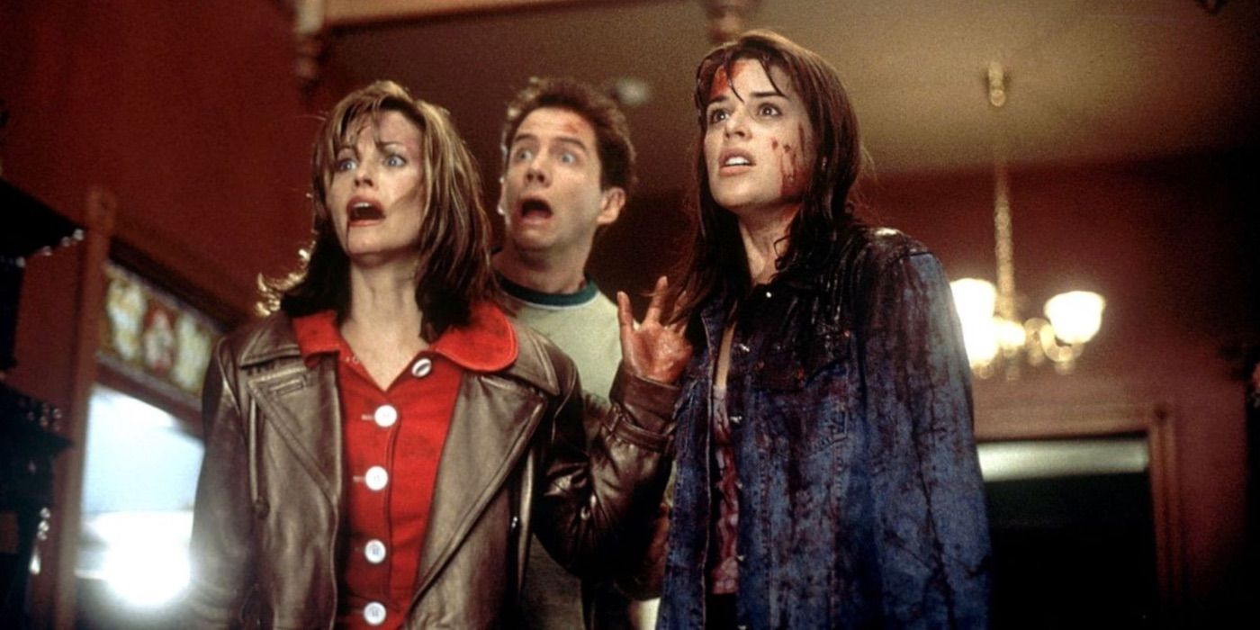 A bloodied Sidney Prescott stands with Gale and Randy in Scream, all looking shocked