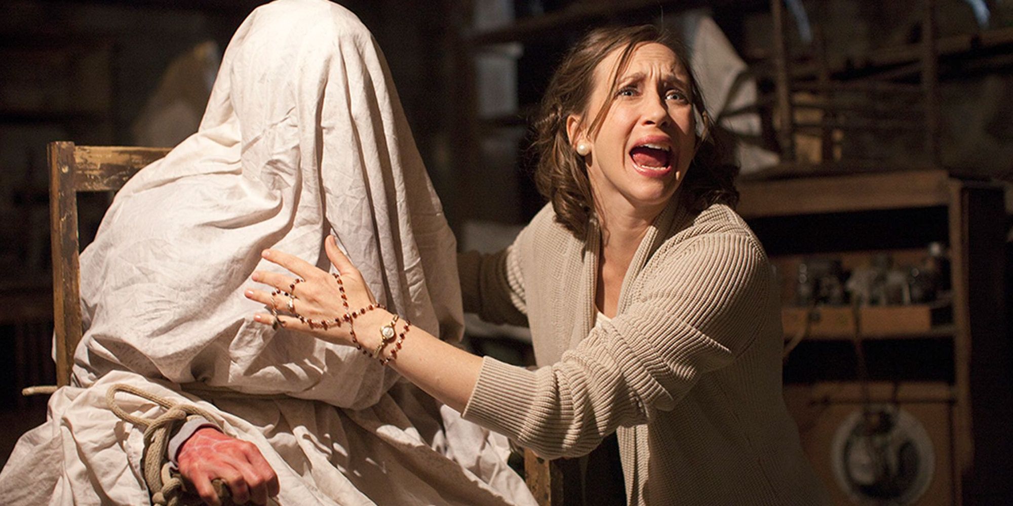 A woman screaming next to a covered figure tied to a chair