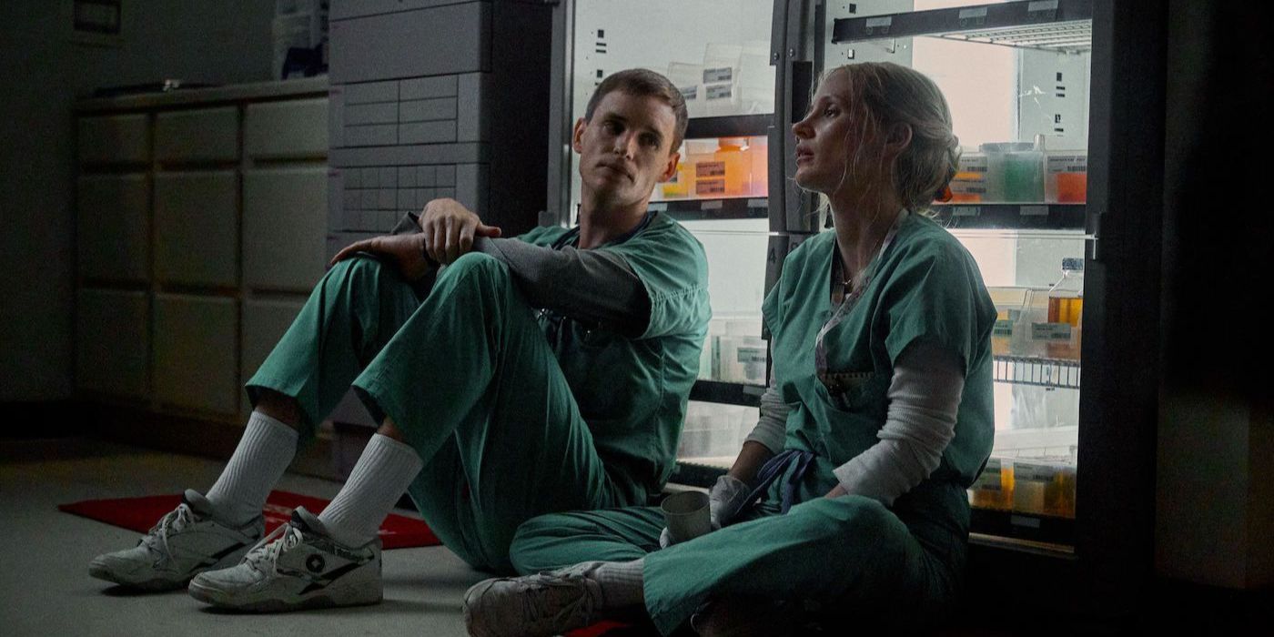 A male and female nurse sitting side by side on a hospital floor in The Good Nurse.