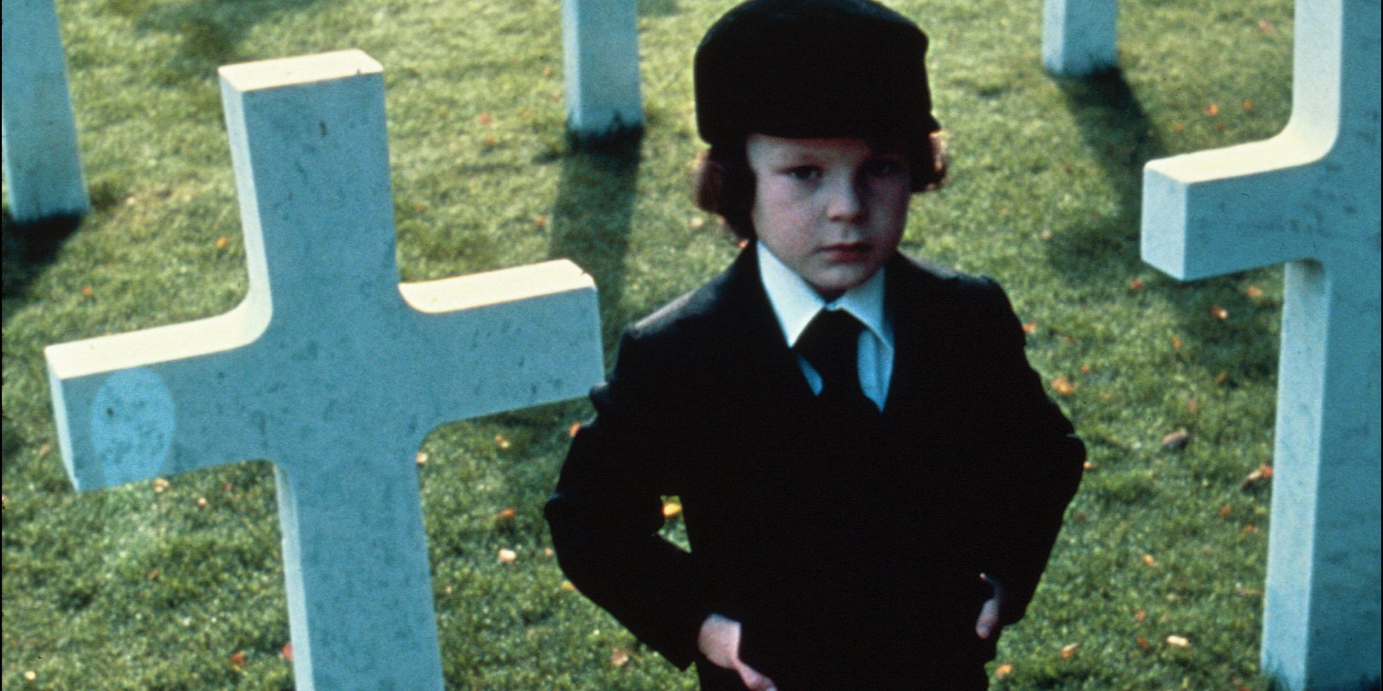 A young boy standing among gravestones