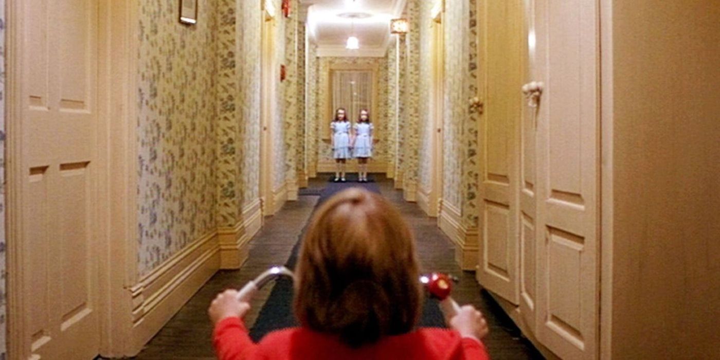 Danny Torrance, played by actor Danny Lloyd, sits on a tricycle in front of two girls in The Shining