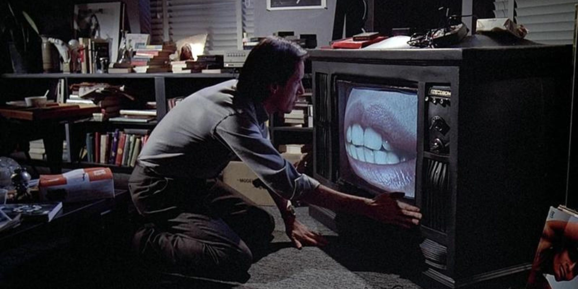 man crouching in front of TV set with an image of a woman's mouth