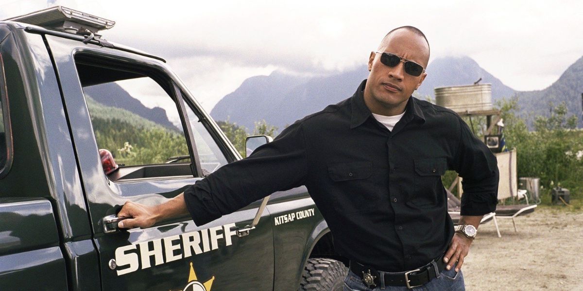 Dwayne Johnson as Chris Vaughn Jr. leaning against a Sheriff truck in Walking Tall (2004)