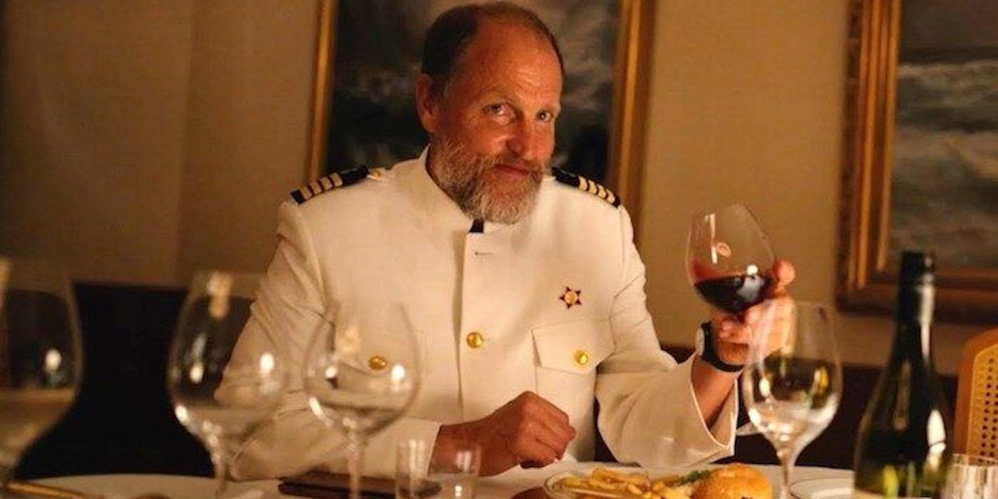 Kapten bersulang dengan segelas wine sambil tersenyum di Triangle Of Sadness.