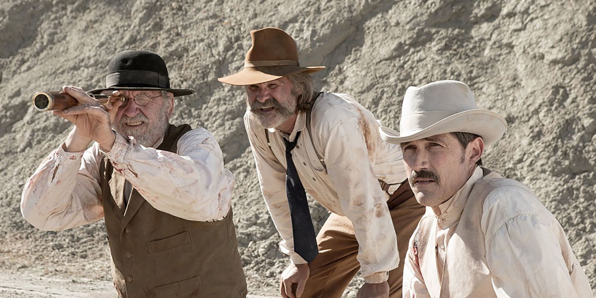 Richard Jenkins, Kurt Russell and Matthew Fox sit in a valley and look into the distance in the movie Bone Tomahawk