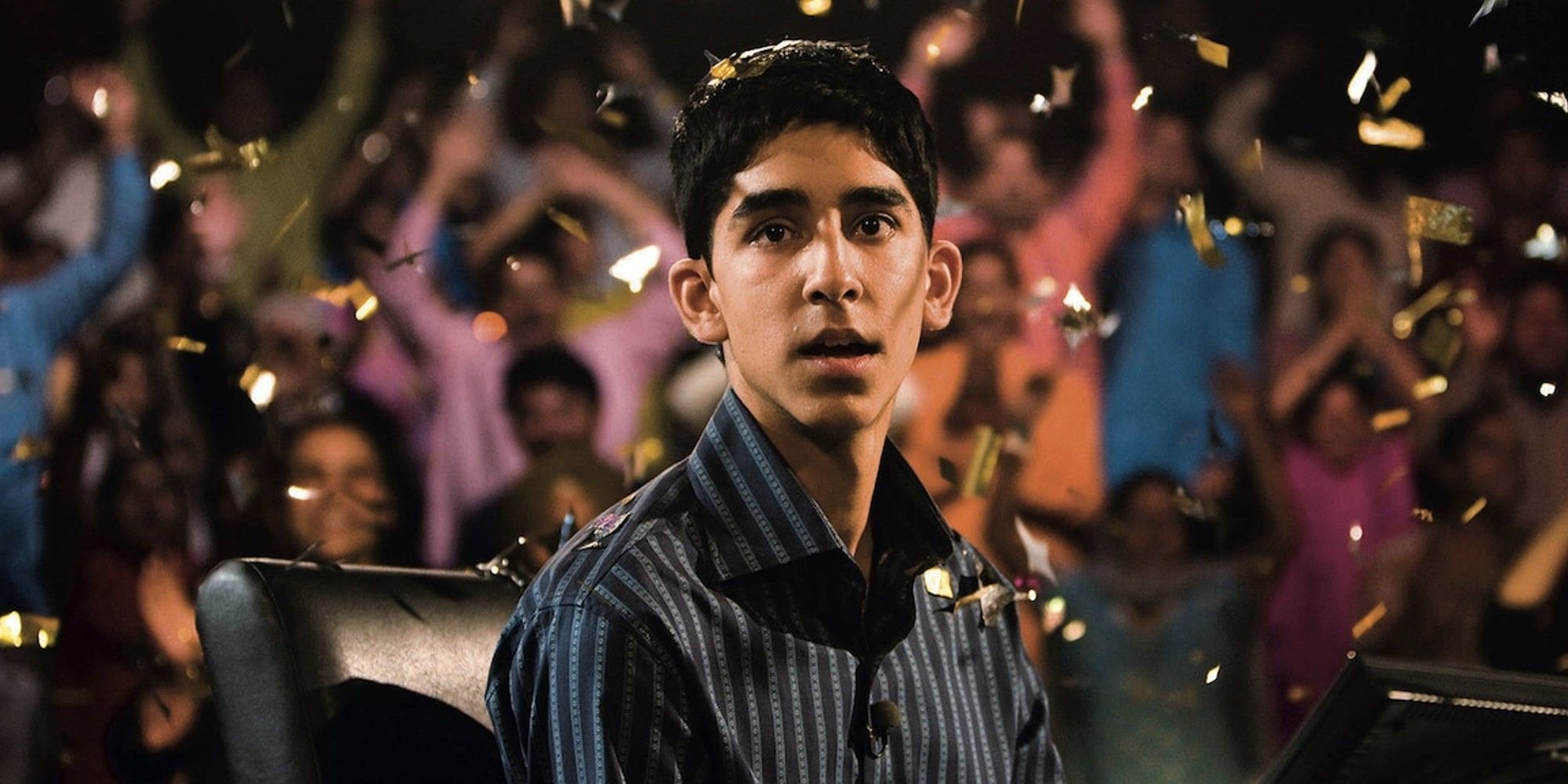 Dev Patel as Jamal, looking surprised while confetti falls around him in Slumdog Millionaire.