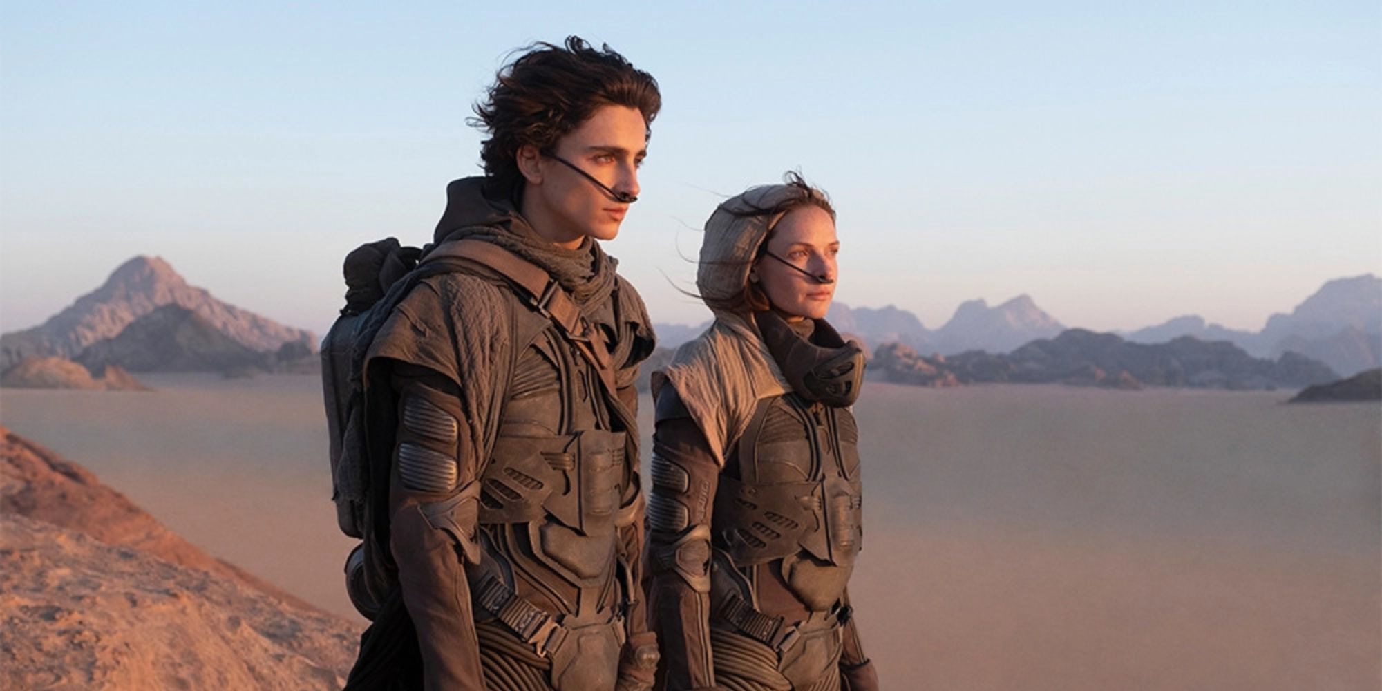 Paul (Timothée Chalamet) and Jessica (Rebecca Ferguson) in the desert looking to the distance in Dune