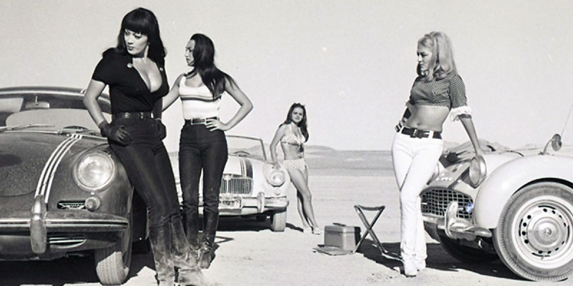 A group of women standing besides cars in the film Faster Pussycat, Kill! Kill! - 1965