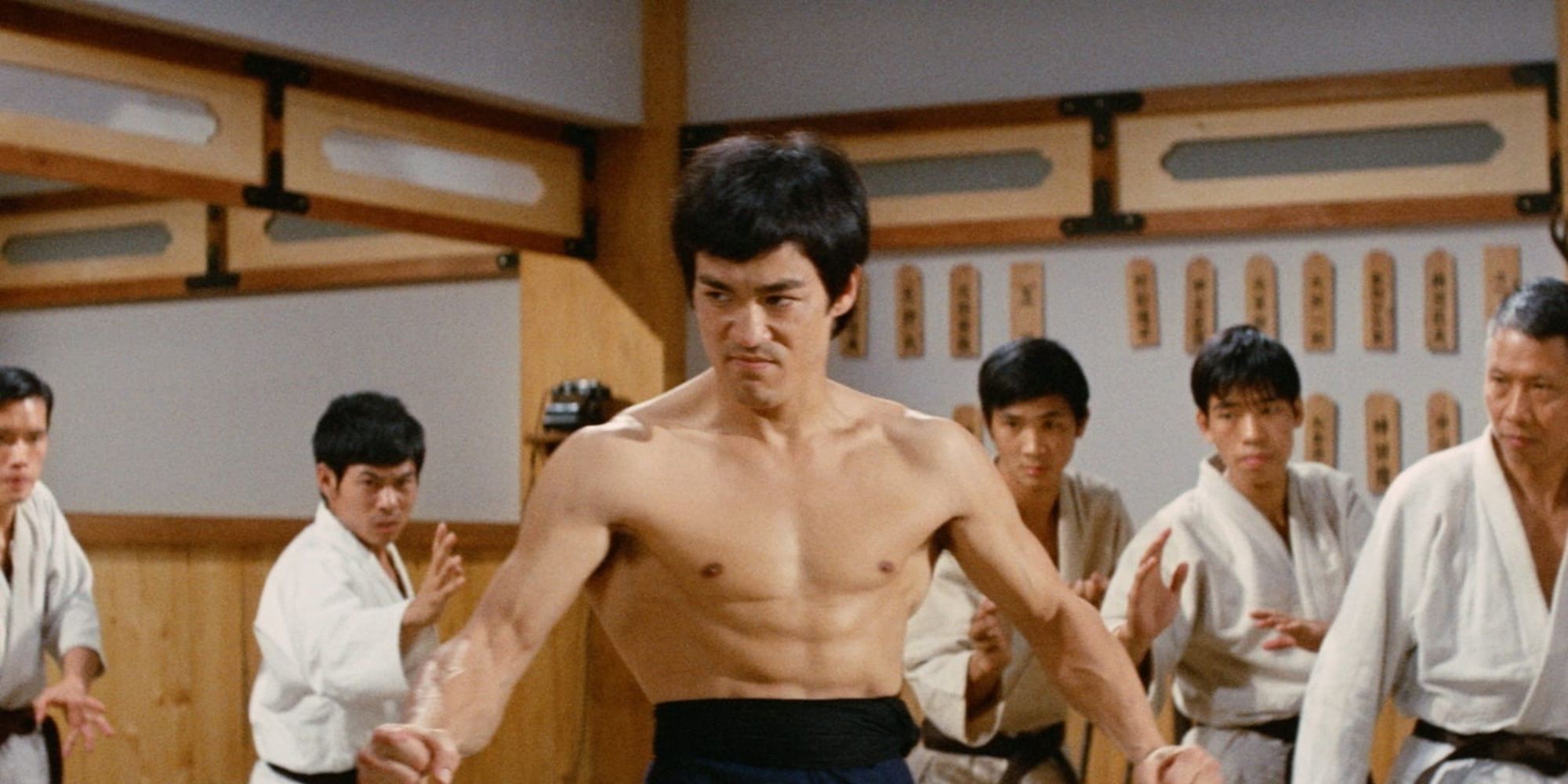 Bruce Lee flexing his core in a dojo in Fist of Fury (1972)