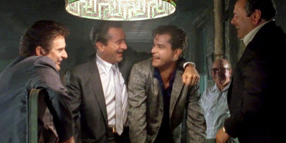 Joe Pesci, Robert De Niro, Ray Liotta dan Paul Sorvino berdiri dan tertawa di sekitar meja di Goodfellas