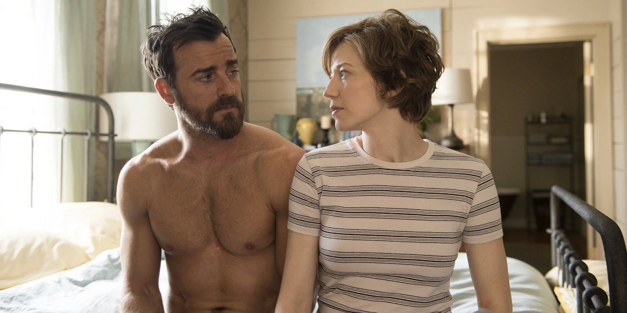 Justin Theroux and Carrie Coon sit side by side on a bed in the HBO series 'The Leftovers'