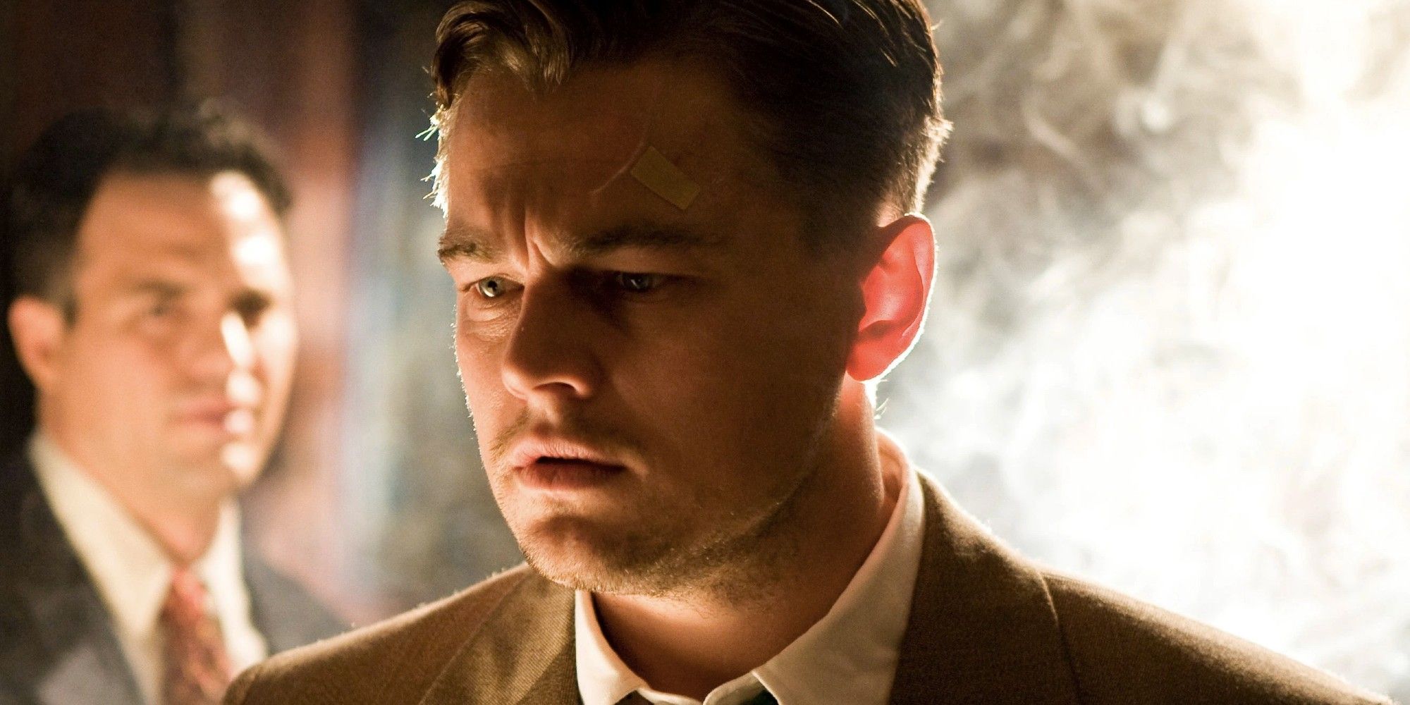 Leonardo DiCaprio looking pensive, while Mark Ruffalo stands in the background, in 'Shutter Island'