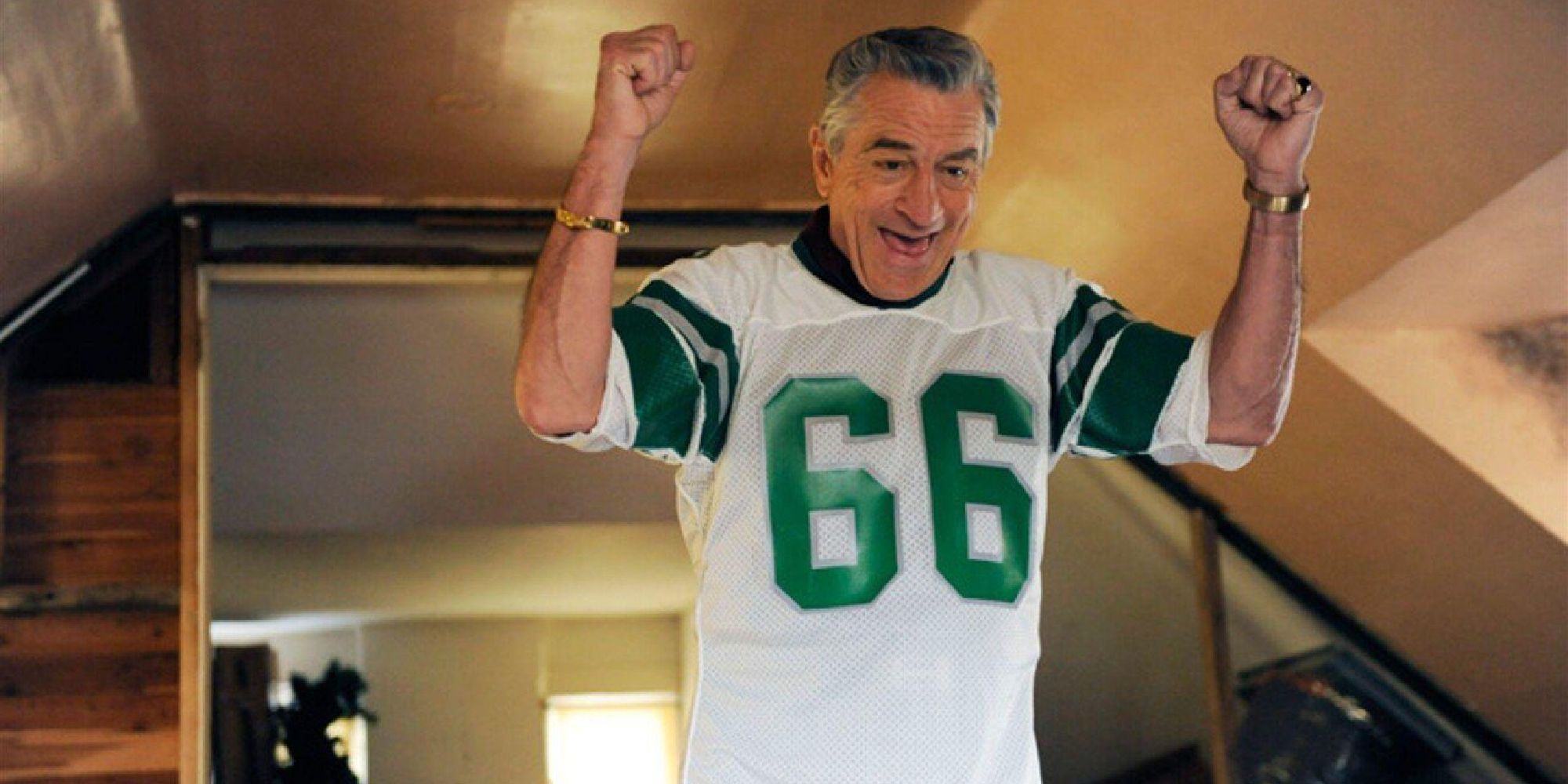 Robert De Niro as Pat Solatano Sr. wearing a football jersey and raising his hands in celebration in Silver Linings Playbook - 2012