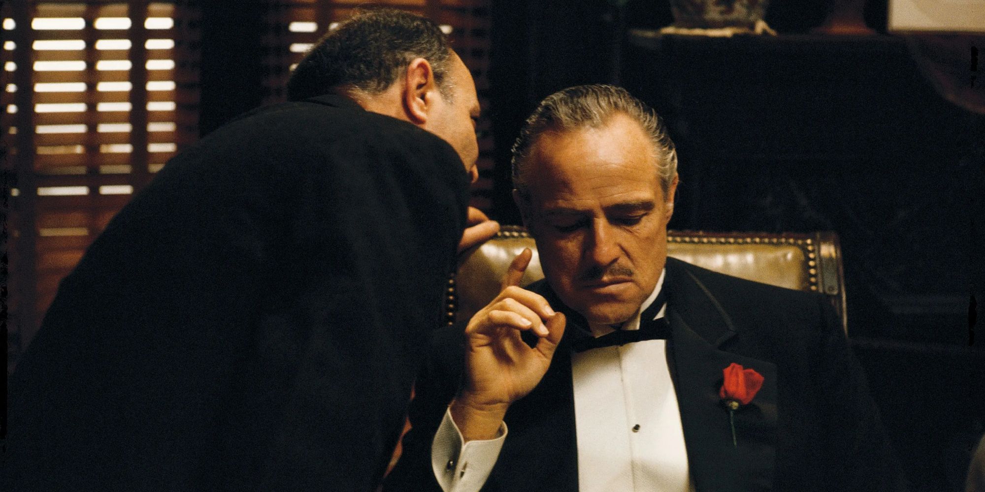 A man whispering Marlon Brando's ear in The Godfather