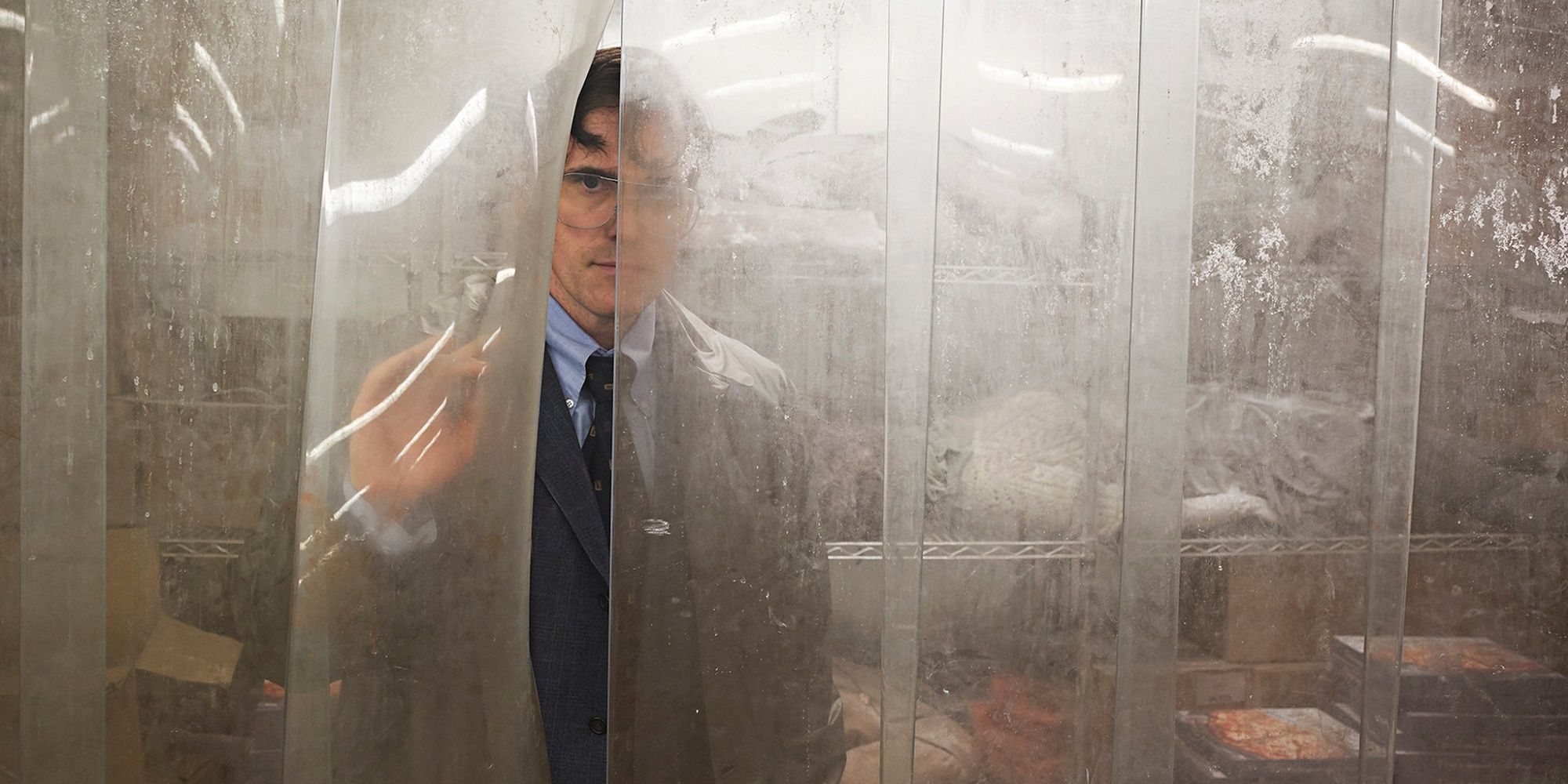 Jack in a suit behind some vinyl curtains in 'The House That Jack Built.'