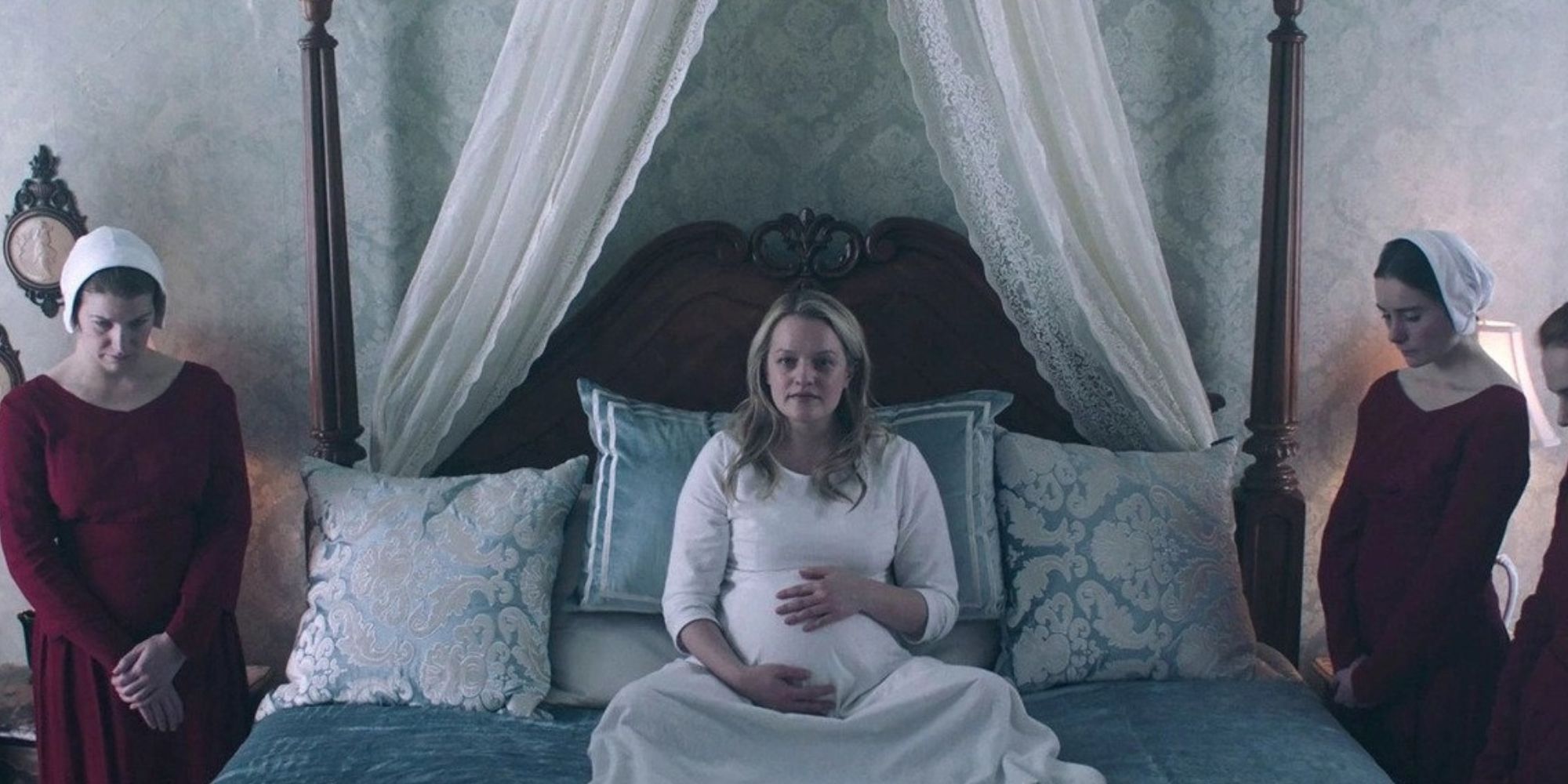 A pregnant Offred in the birthing suite, surrounded by handmaids