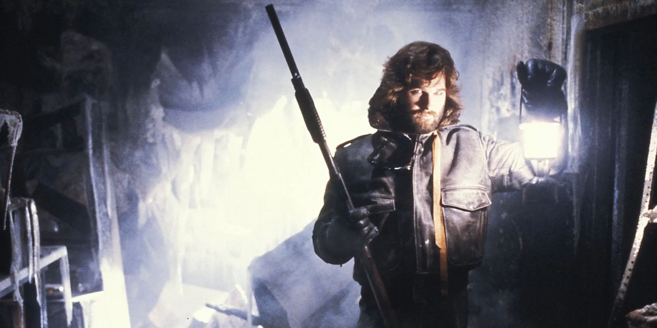 Kurt Russell holding a shotgun and a lantern in The Thing