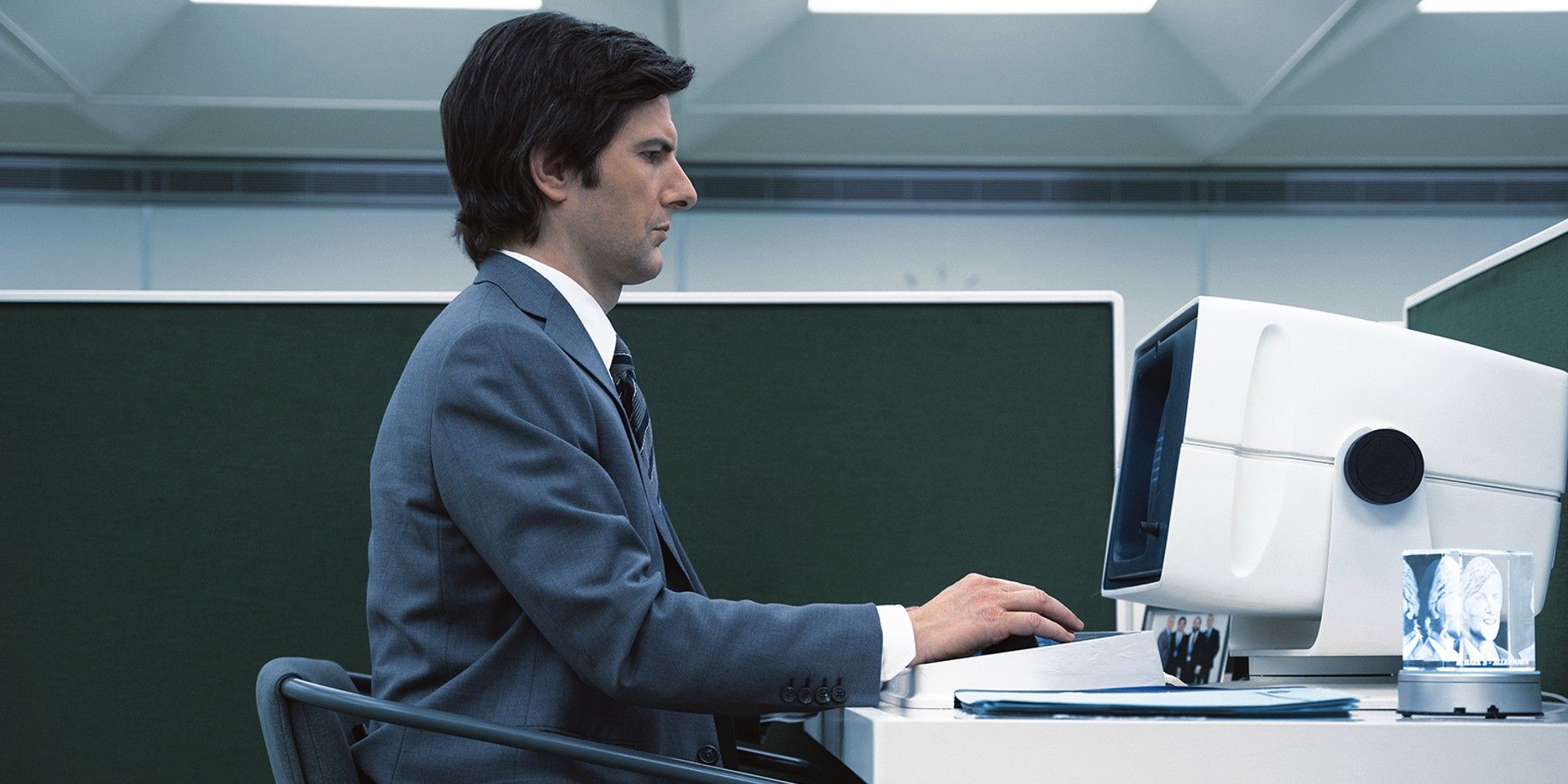 Adam Scott in Severance sitting at a work computer, back straight typing.