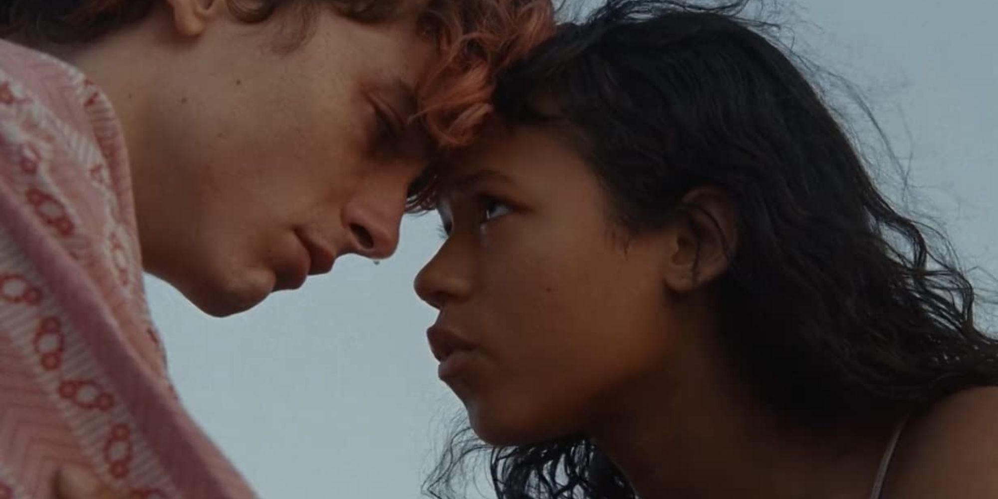 A teenage girl and boy press their foreheads together while gazing into each other's eyes