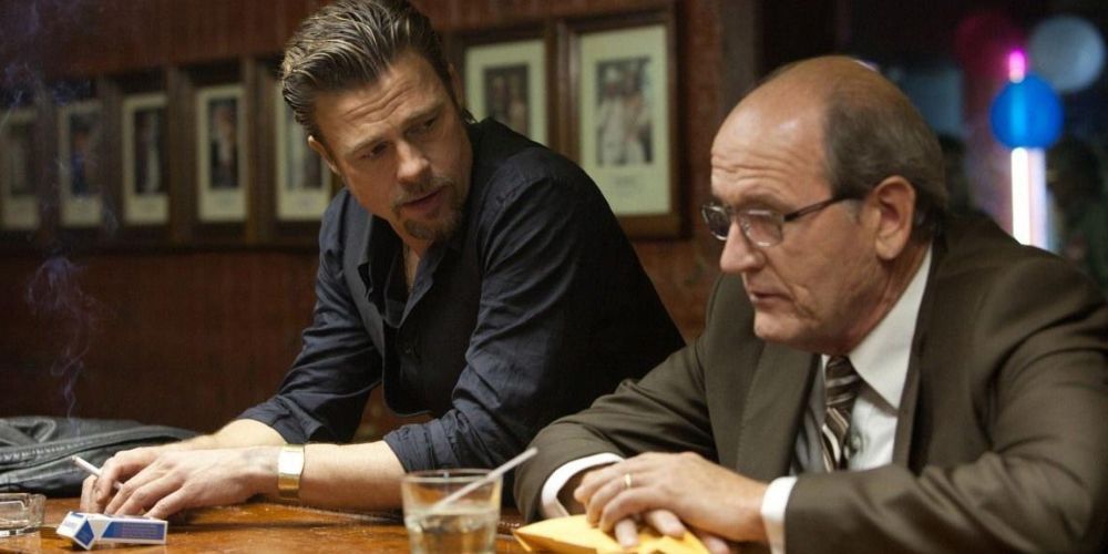 Brad Pitt conversando com Richard Jenkins em um bar em Killing Them Softly