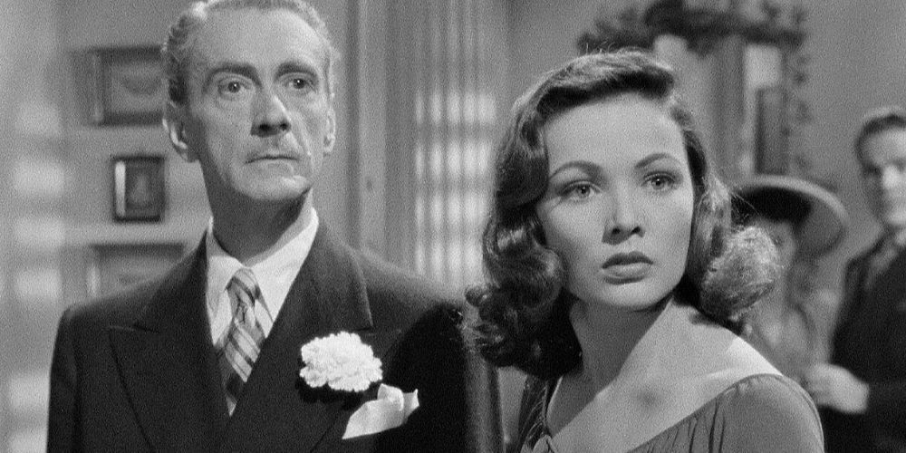 Clifton Webb standing next to Gene Tierney both looking forward in Laura