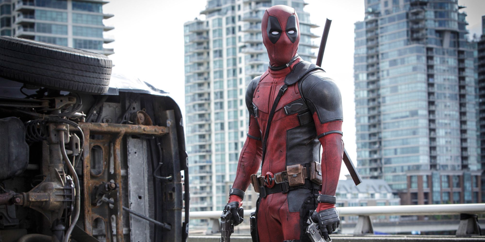Deadpool standing on the freeway holding a gun.
