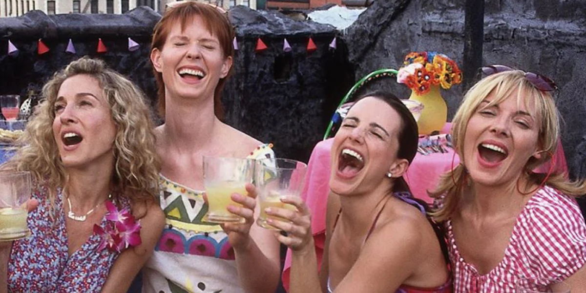 Carrie, Miranda, Charlotte, and Samantha laughing for a photo in Sex and the City