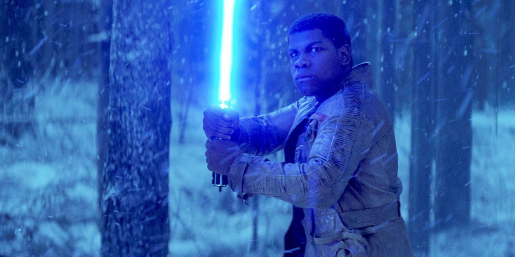 Finn holding a lightsaber in the snow from 'Star Wars: Episode VII - The Force Awakens'