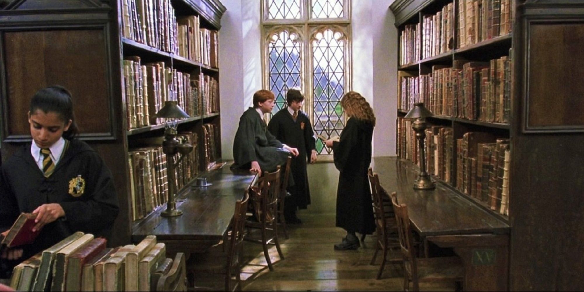 Harry Potter avec Ron et Hermione dans la bibliothèque de Poudlard.