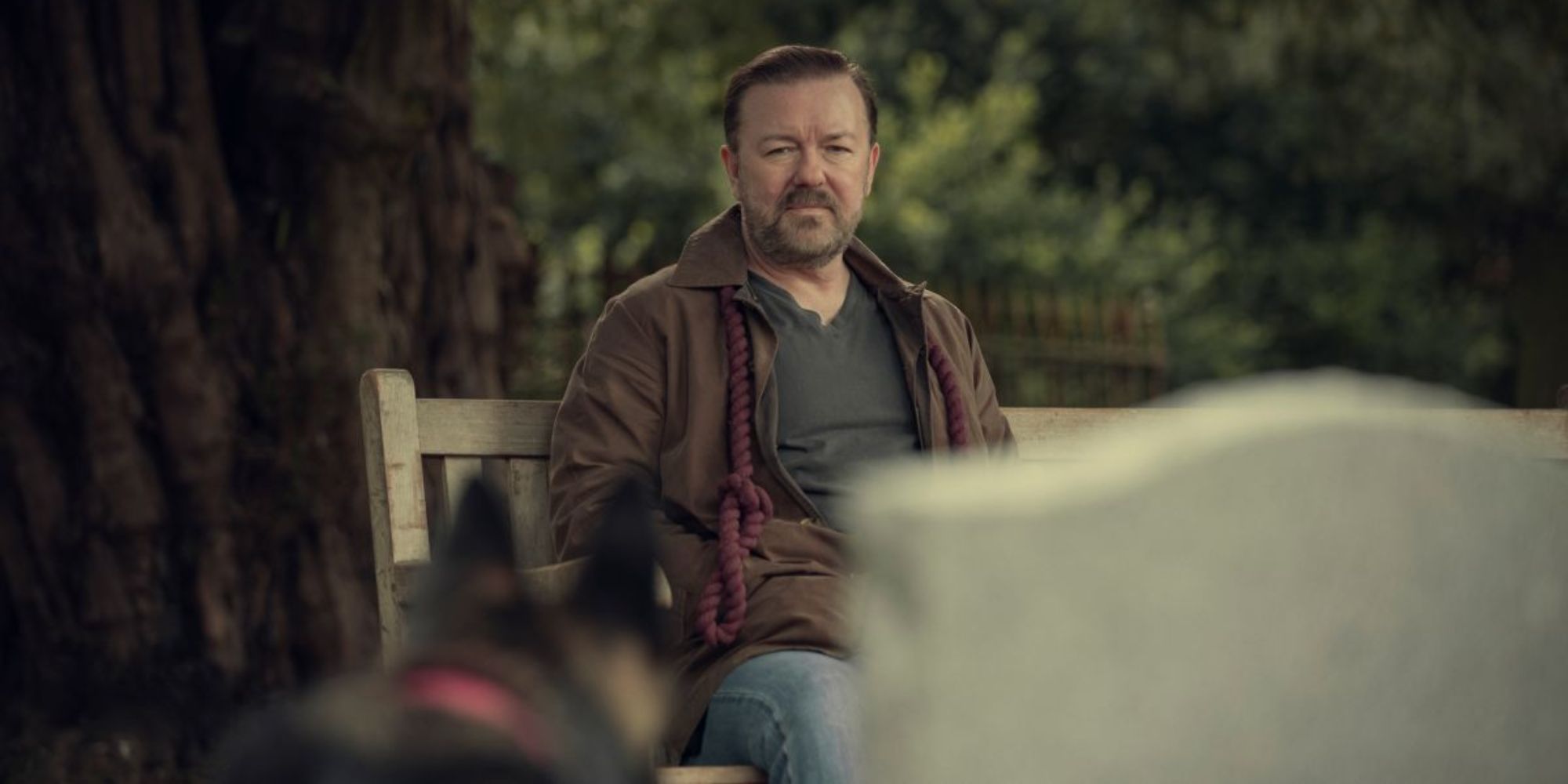 A man sitting on the bench looking sullen in a scene from After Life.