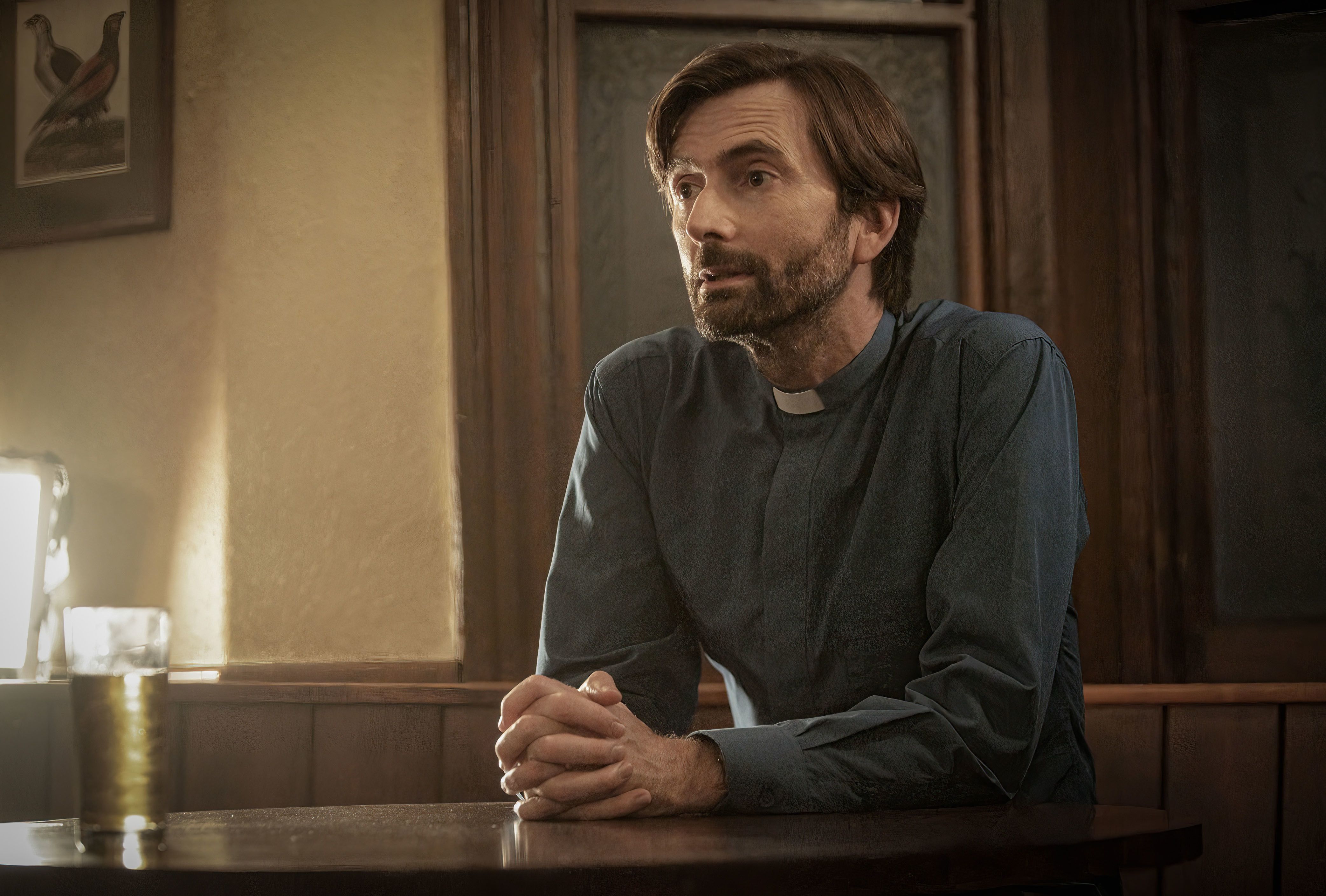 David Tennant as Pastor Henry seated at a desk in Inside Man