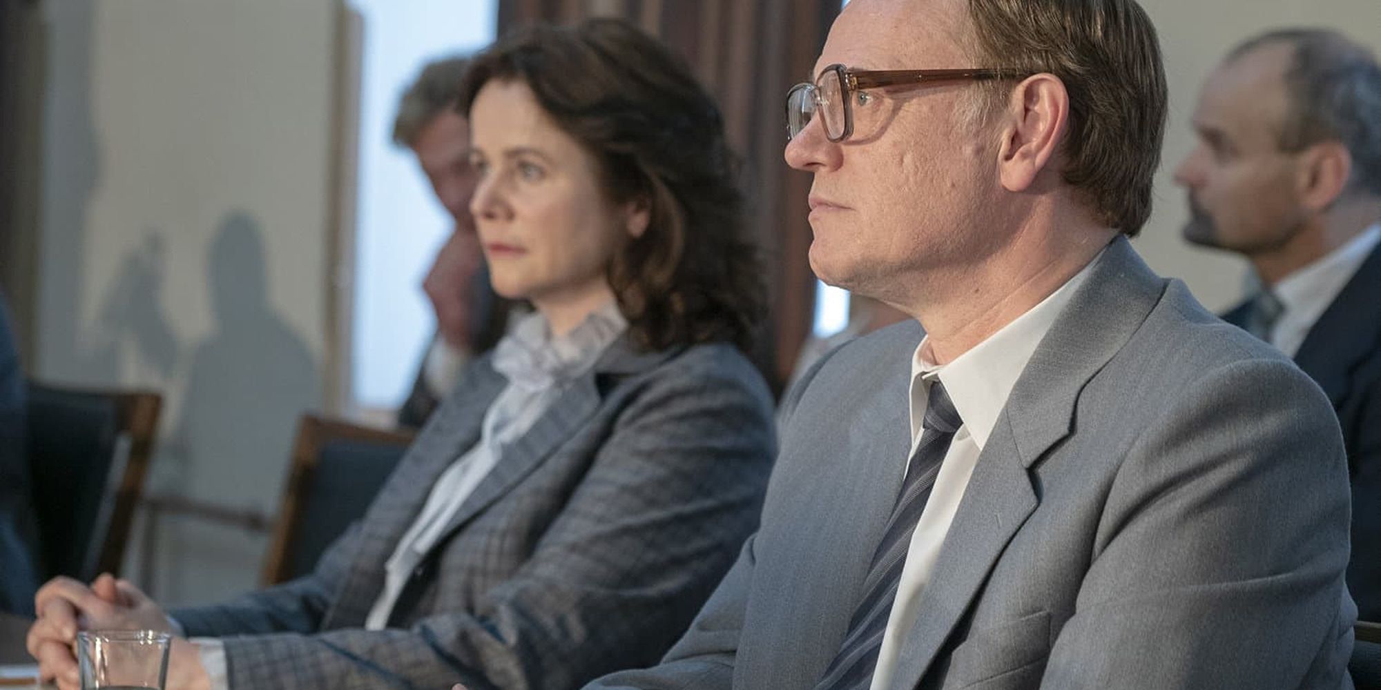 Jared Harris and Emily Watson with suits sitting at a table, from Chernobyl
