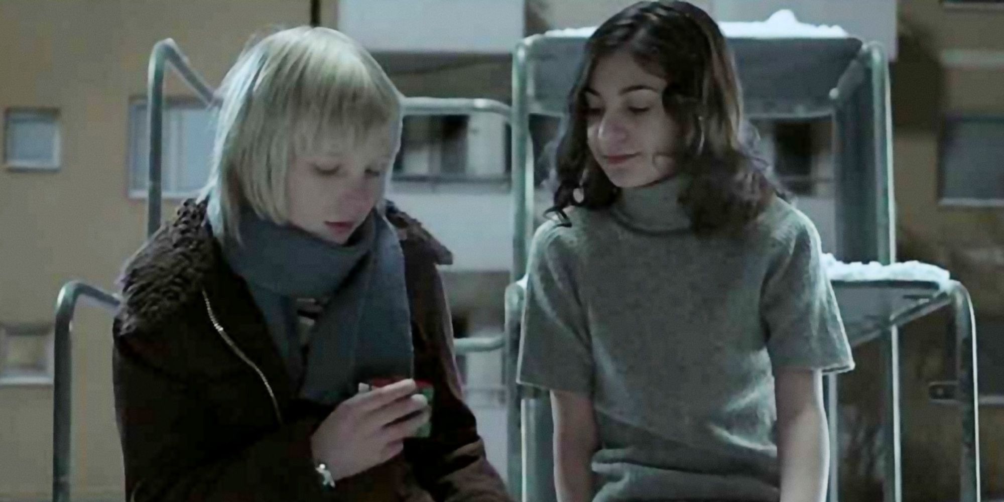 Deux enfants assis sur un ensemble de jeu dans la neige dans Let the Right One in