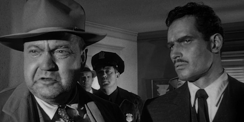 Orson Welles talking and standing next to Charlton Heston in Touch of Evil