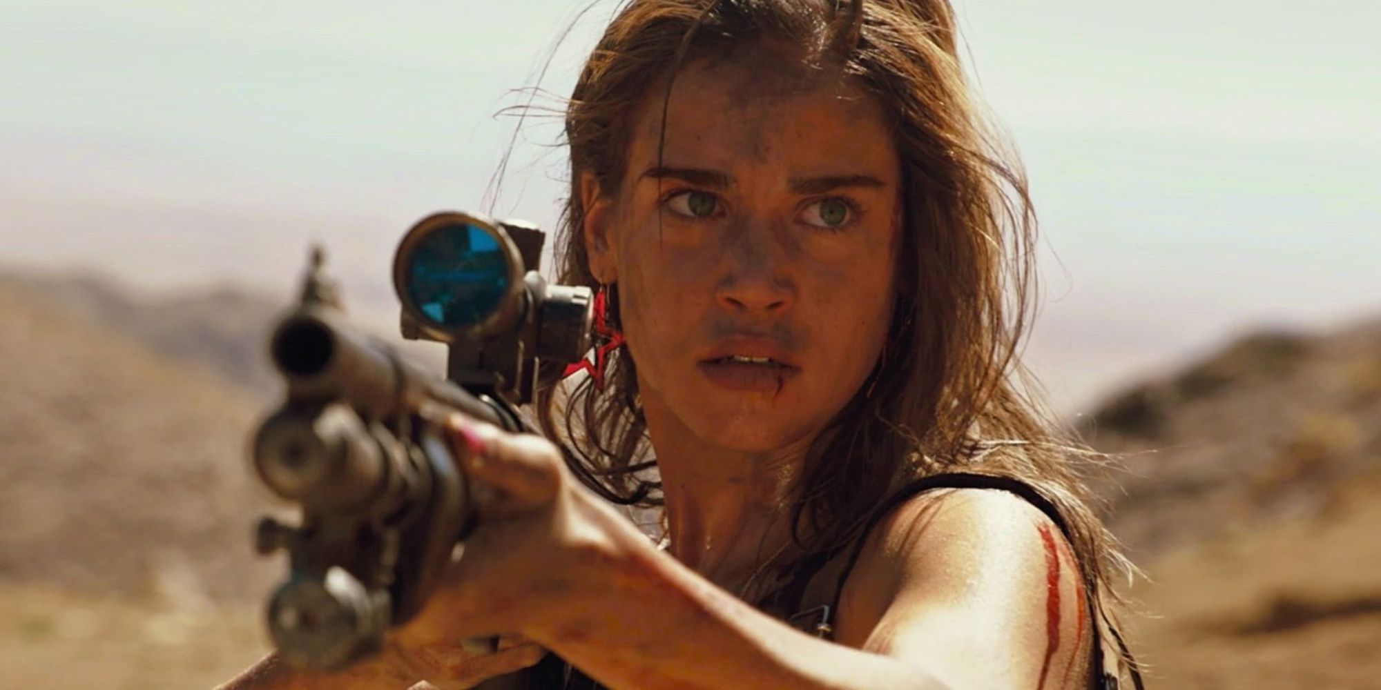 Matilda Lutz holding a rifle in the desert in Revenge