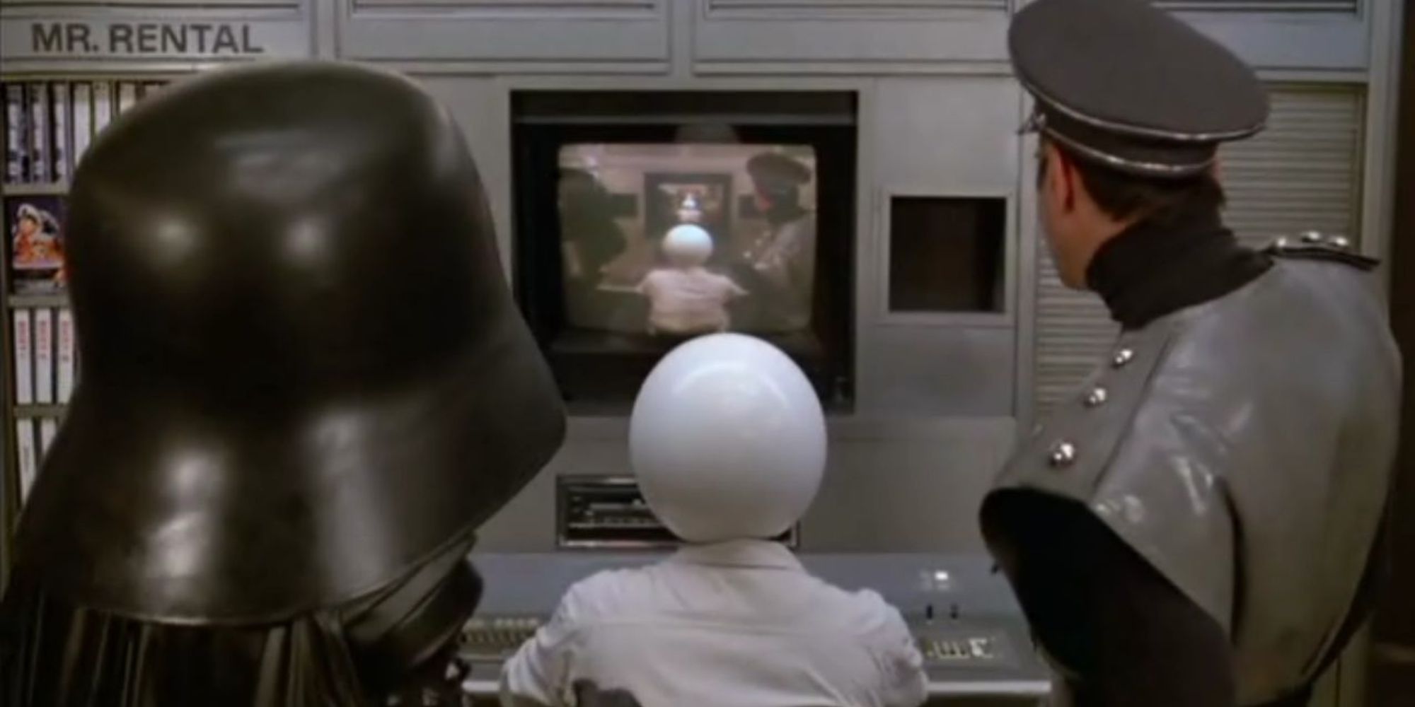 Dark Helmet, Colonel Sandurz, and a Spaceball look at a screen, which is filled with the exact same image that the audience sees