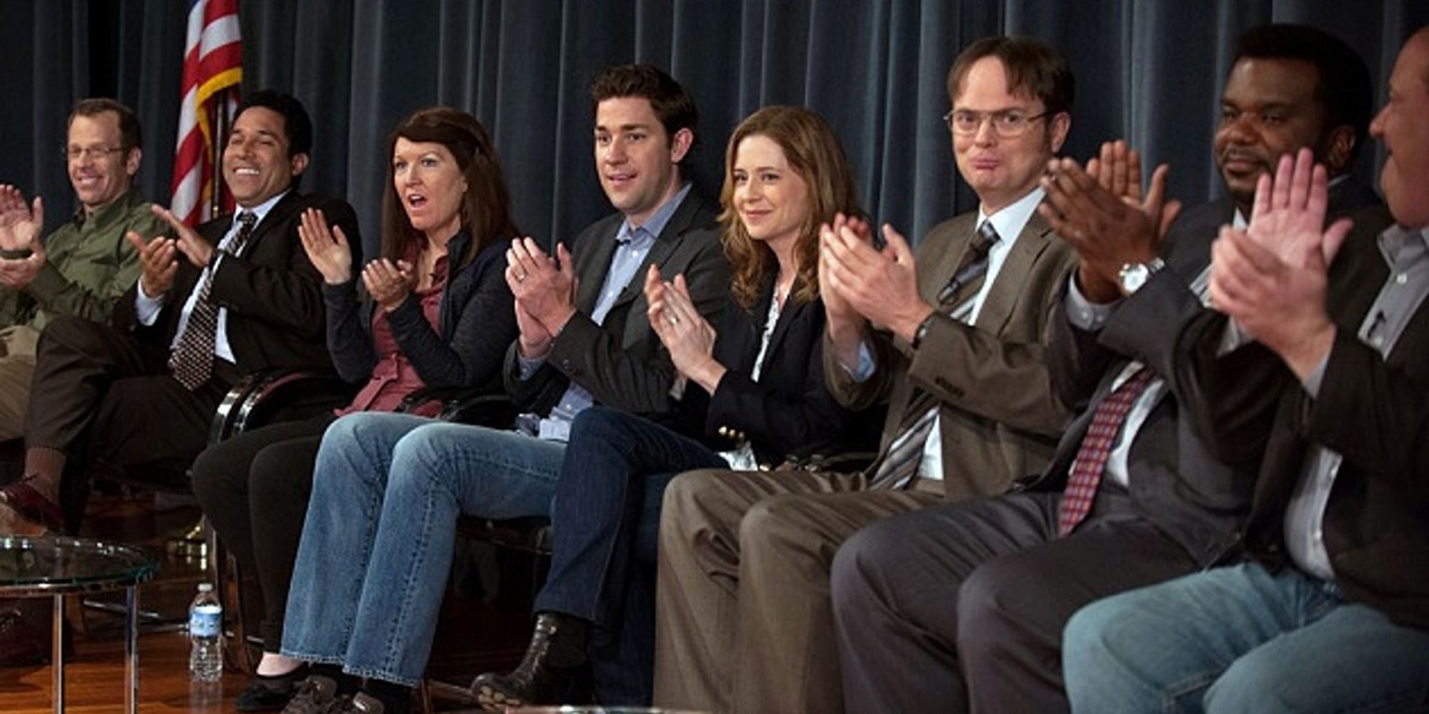 um grupo de personagens em uma conferência, batendo palmas