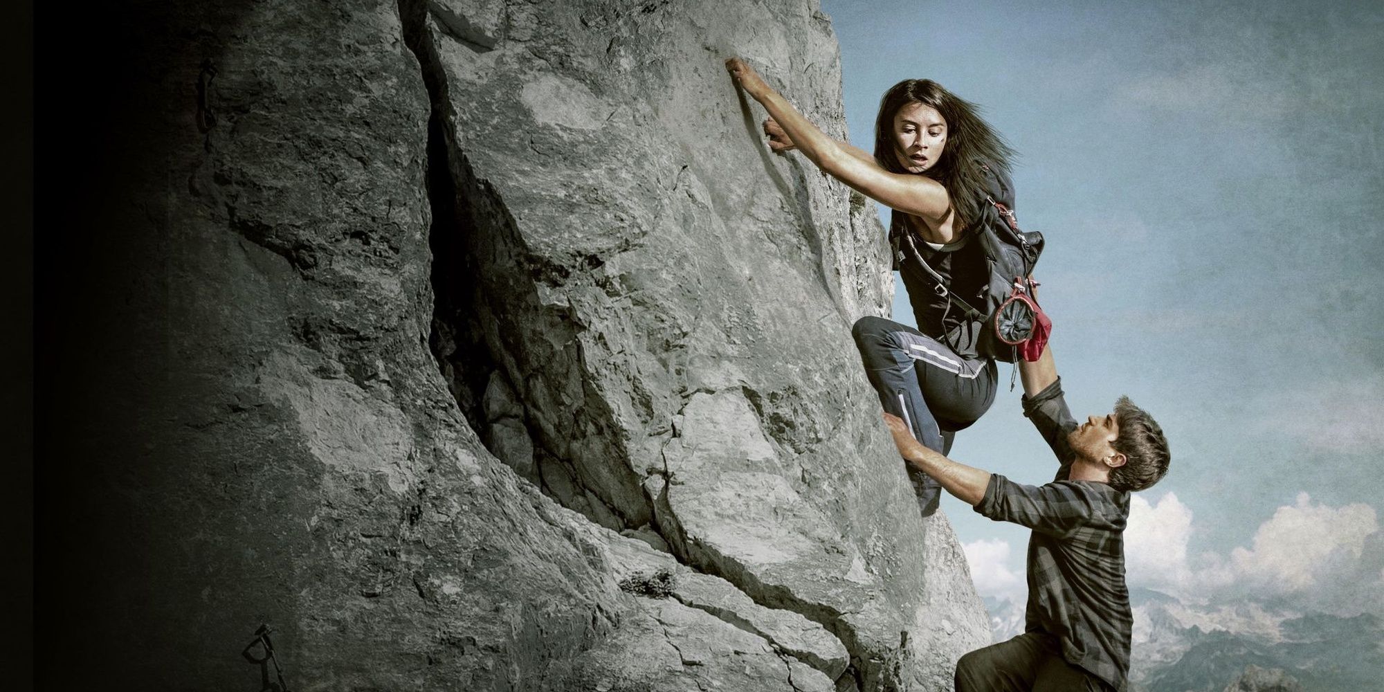 A woman climbing a mountain as a man tries to pull her off