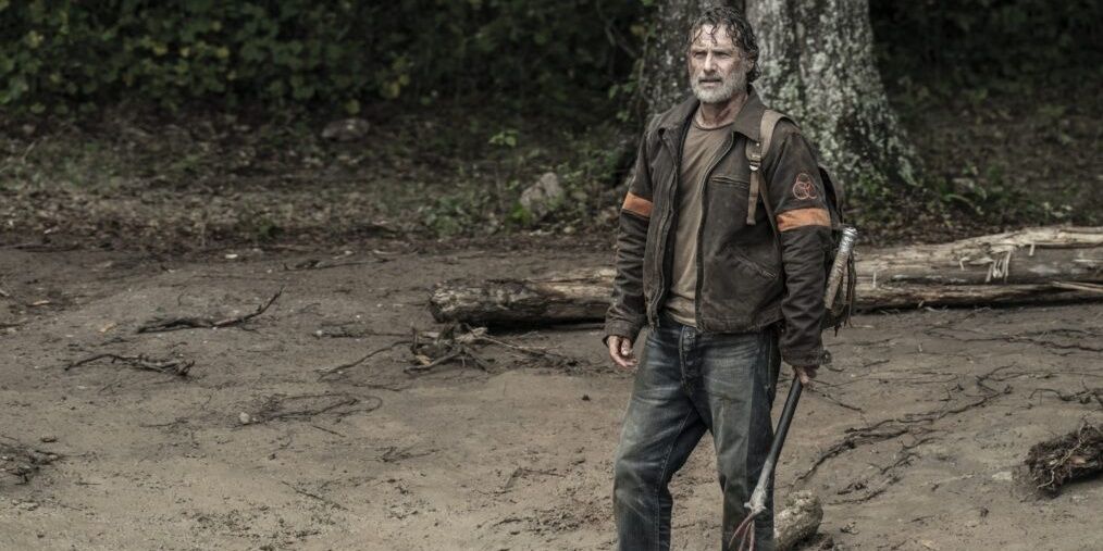 Rick Grimes stands on a muddy bank wielding a pronged weapon in 'The Walking Dead' series finale.