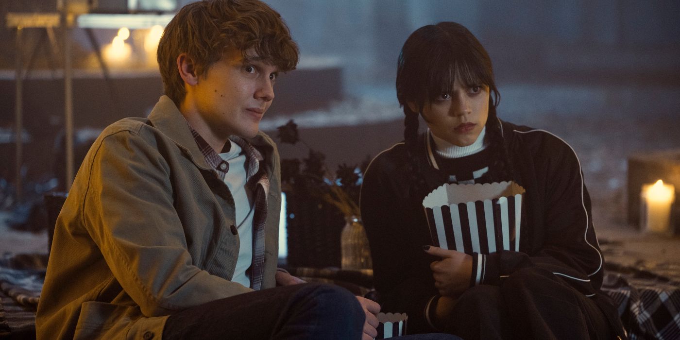 Hunter Doohan as Tyler and Jenna Ortega as Wednesday watching a movie on a couch in Netflix's Wednesday 