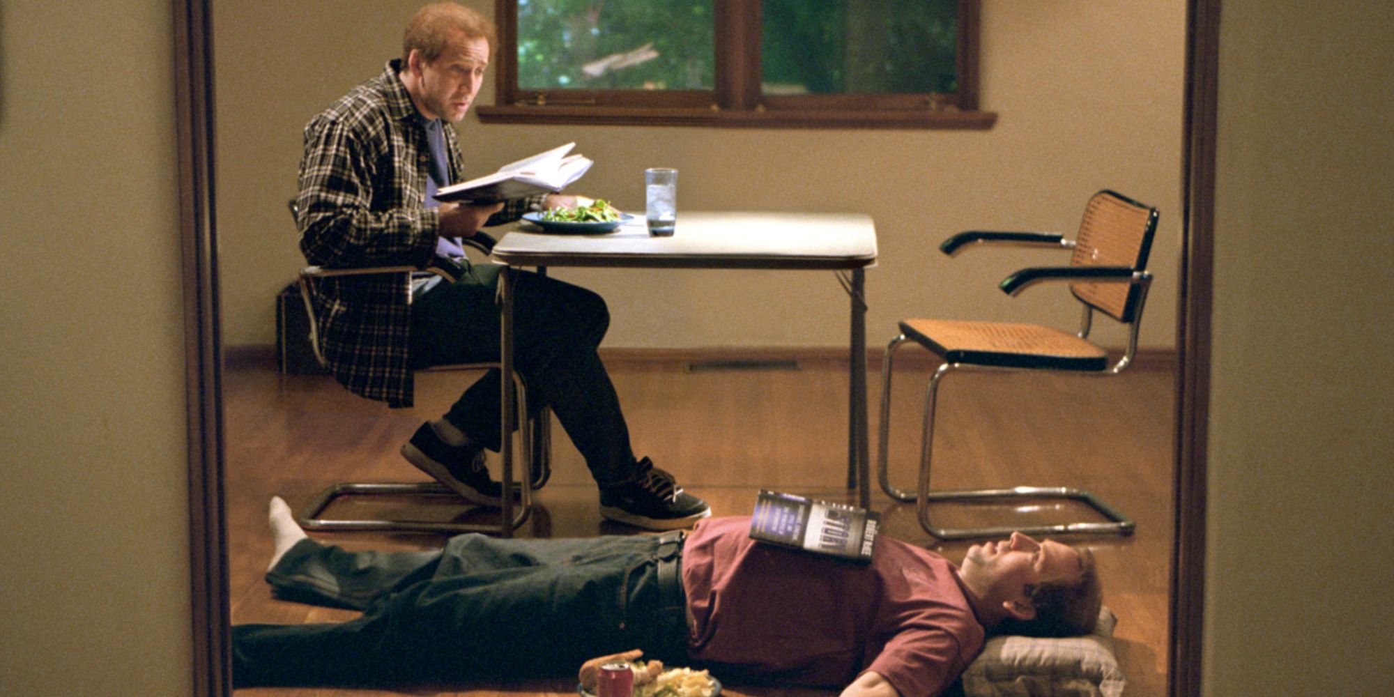Charlie lying on the floor while Dennis reads a book in Adaptation