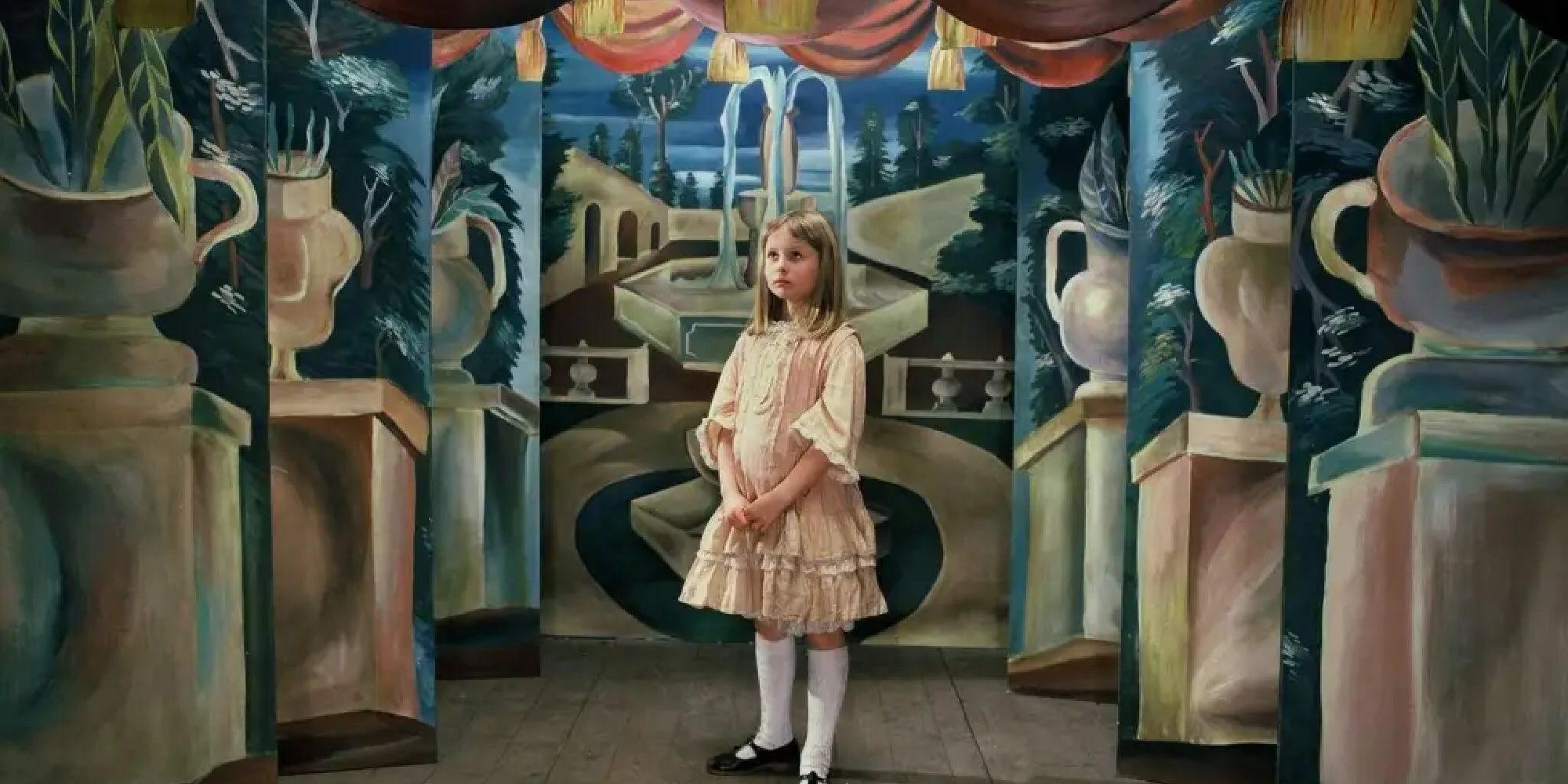 A young woman standing in front of a group of paintings in Alice