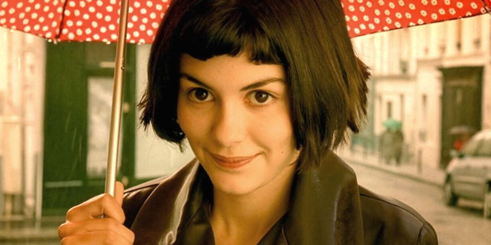 Audrey Tautou souriant légèrement en tenant un parapluie dans Amélie