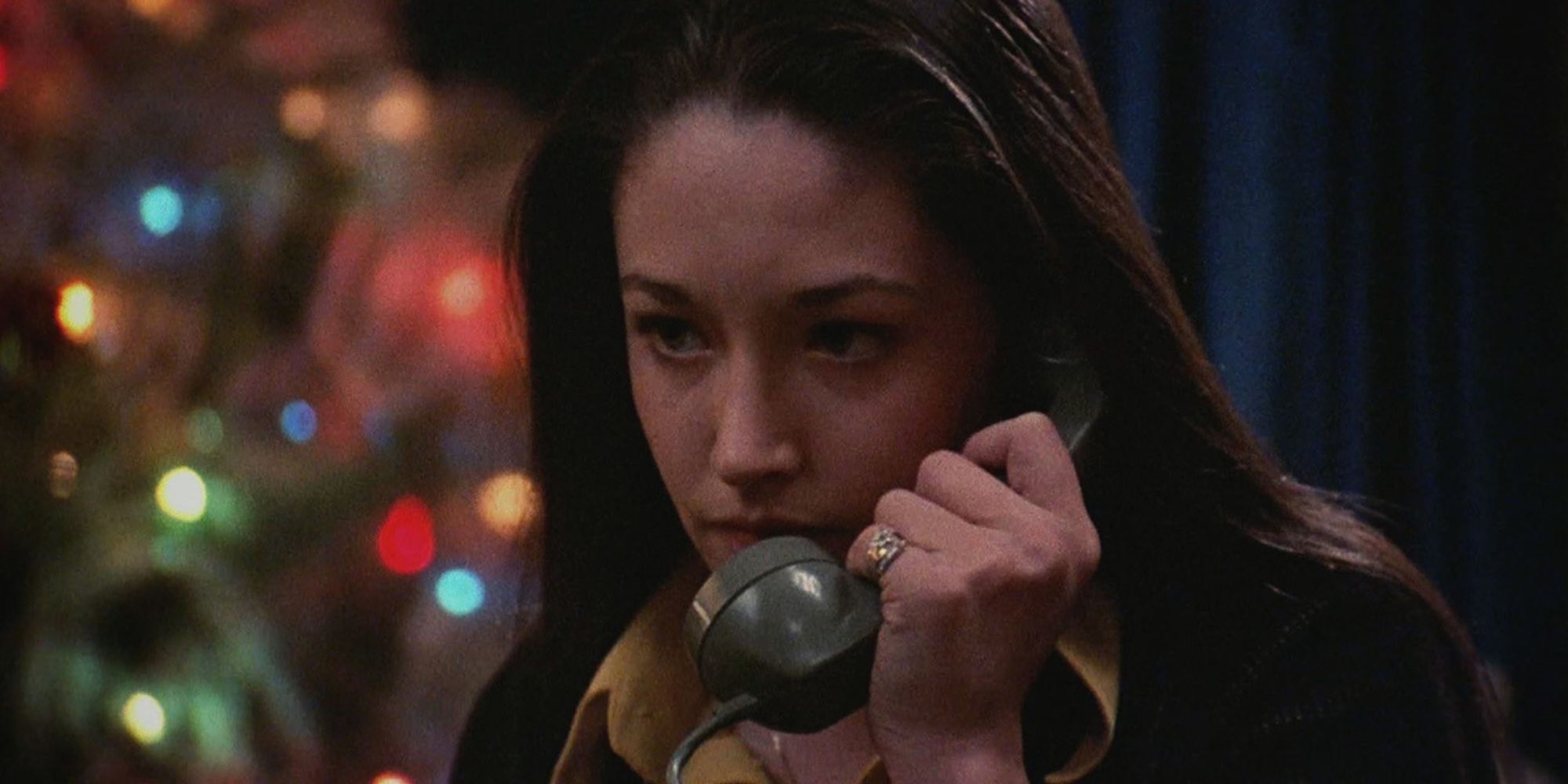 Woman holding a telephone with a Christmas tree in the background