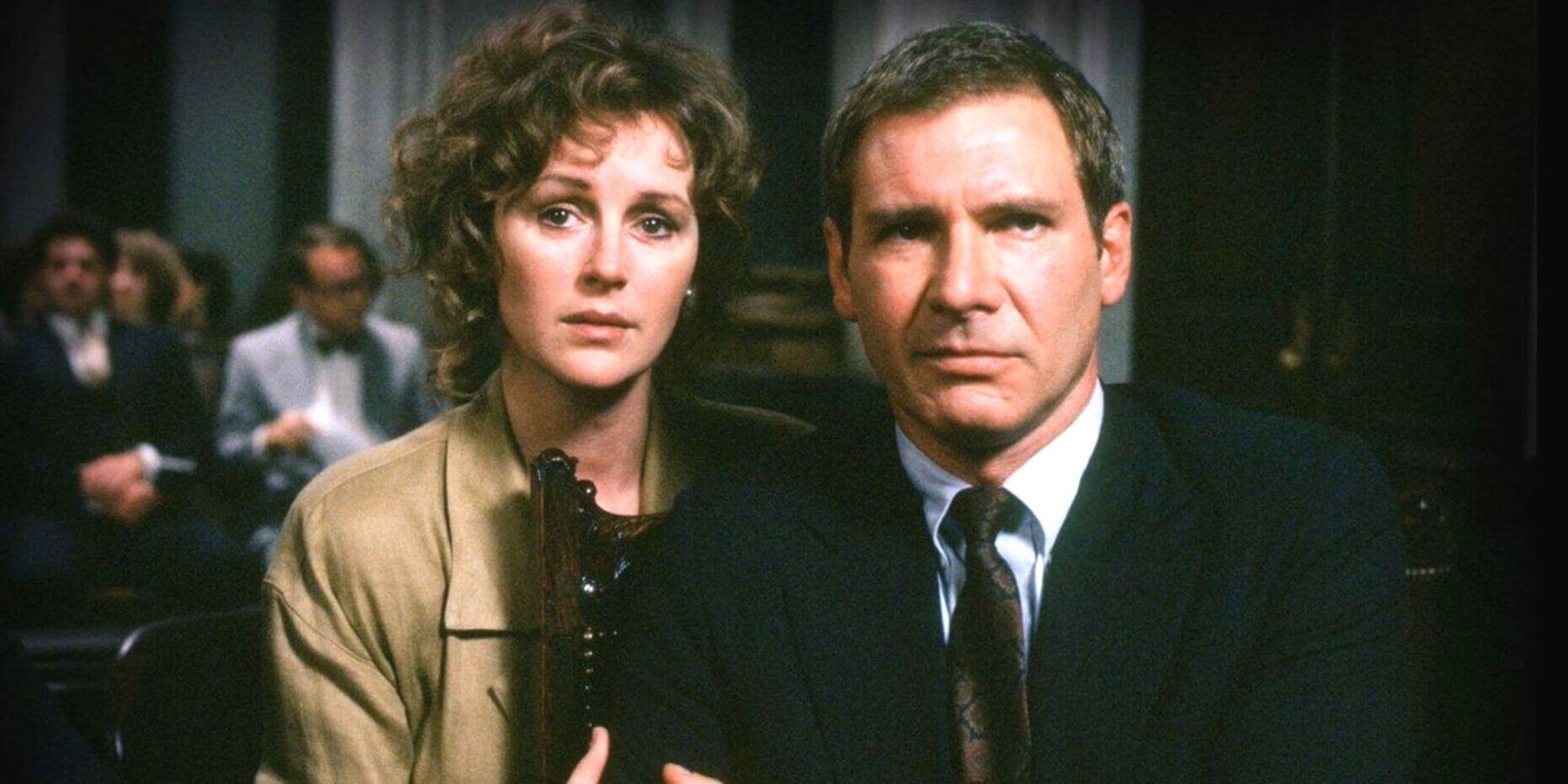 Bonnie Bedelia standing close next to Harrison Ford in a court room in Presumed Innocent