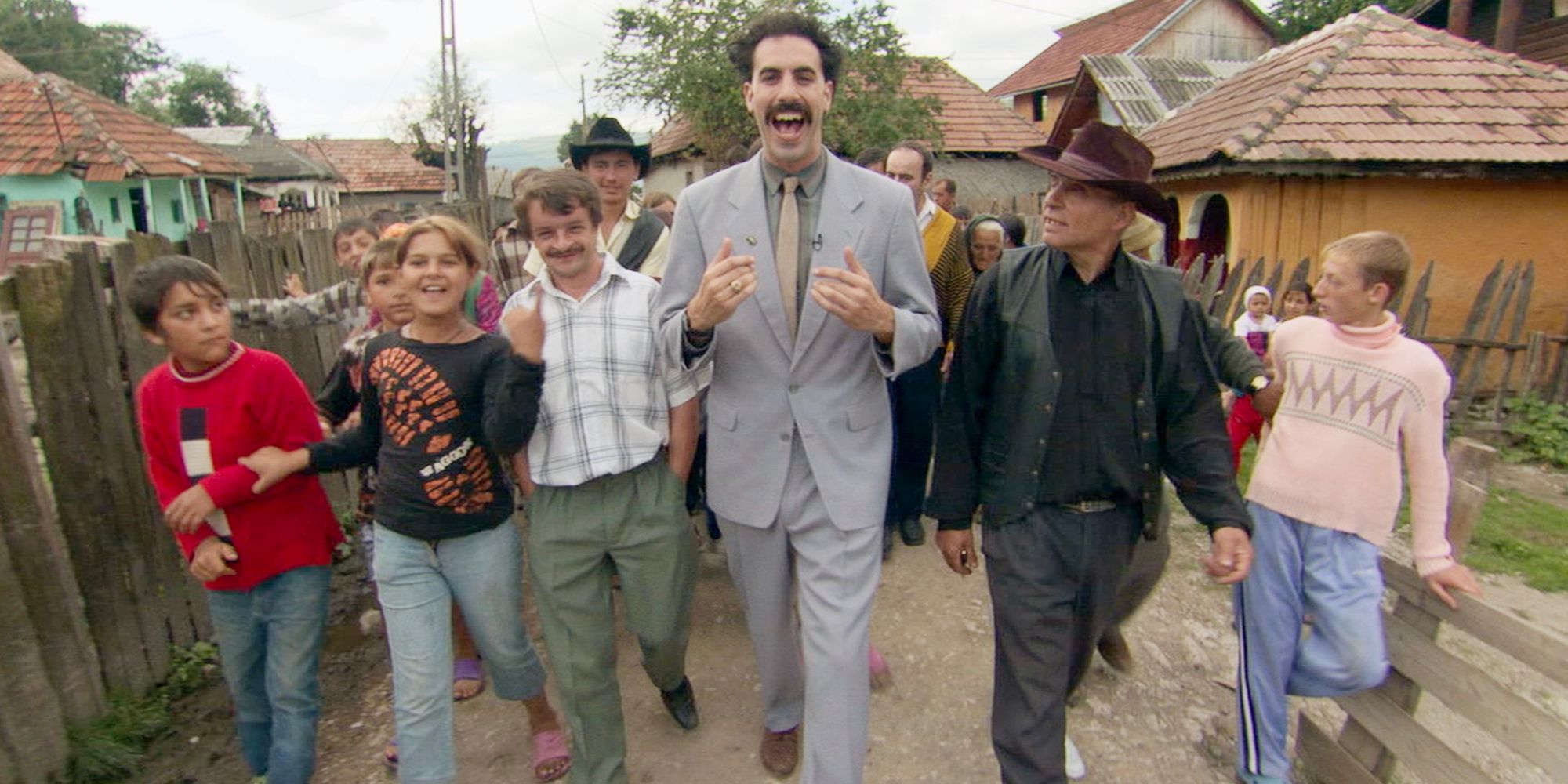 Borat caminha pelas ruas de uma cidade do Cazaquistão. 